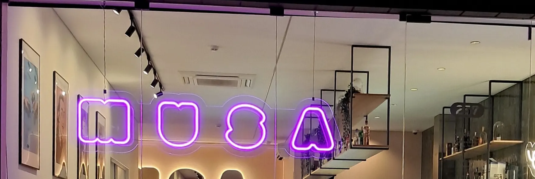 A montra da Musa à noite, com o néon MUSA e a sala iluminada lá dentro.