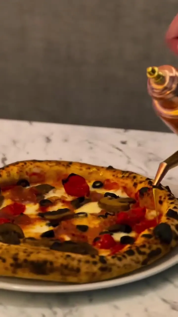 Pizza napolitana acabada de sair do forno, com a borda tostada, na mesa de mármore da Musa.